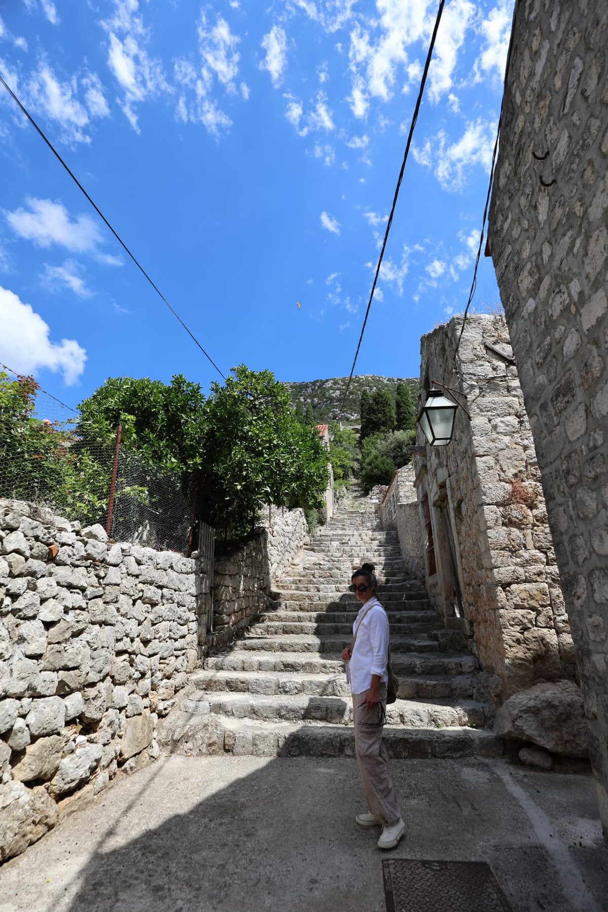 A person climbing old stone steps in a Dalmatian coastal town