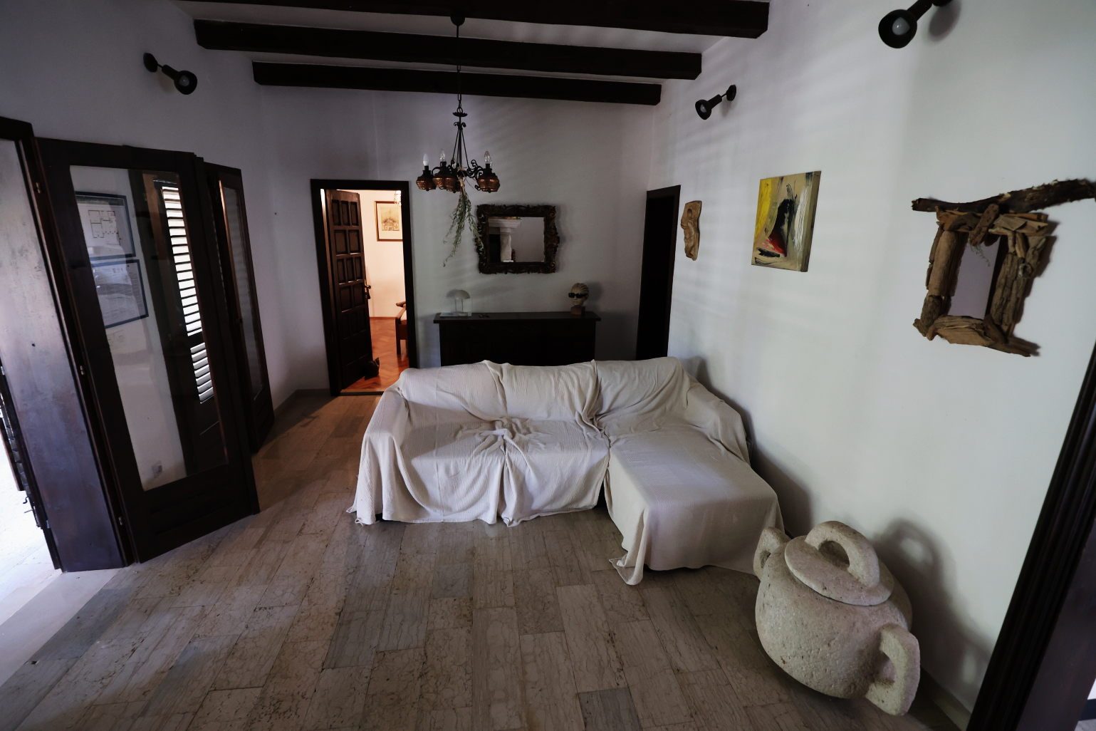 Sitting room with beamed ceiling, covered sofa and a stone jar