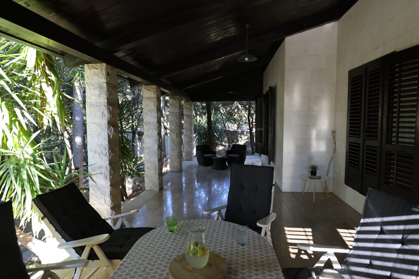 The covered terrace with stone pillars, a table set in the shade