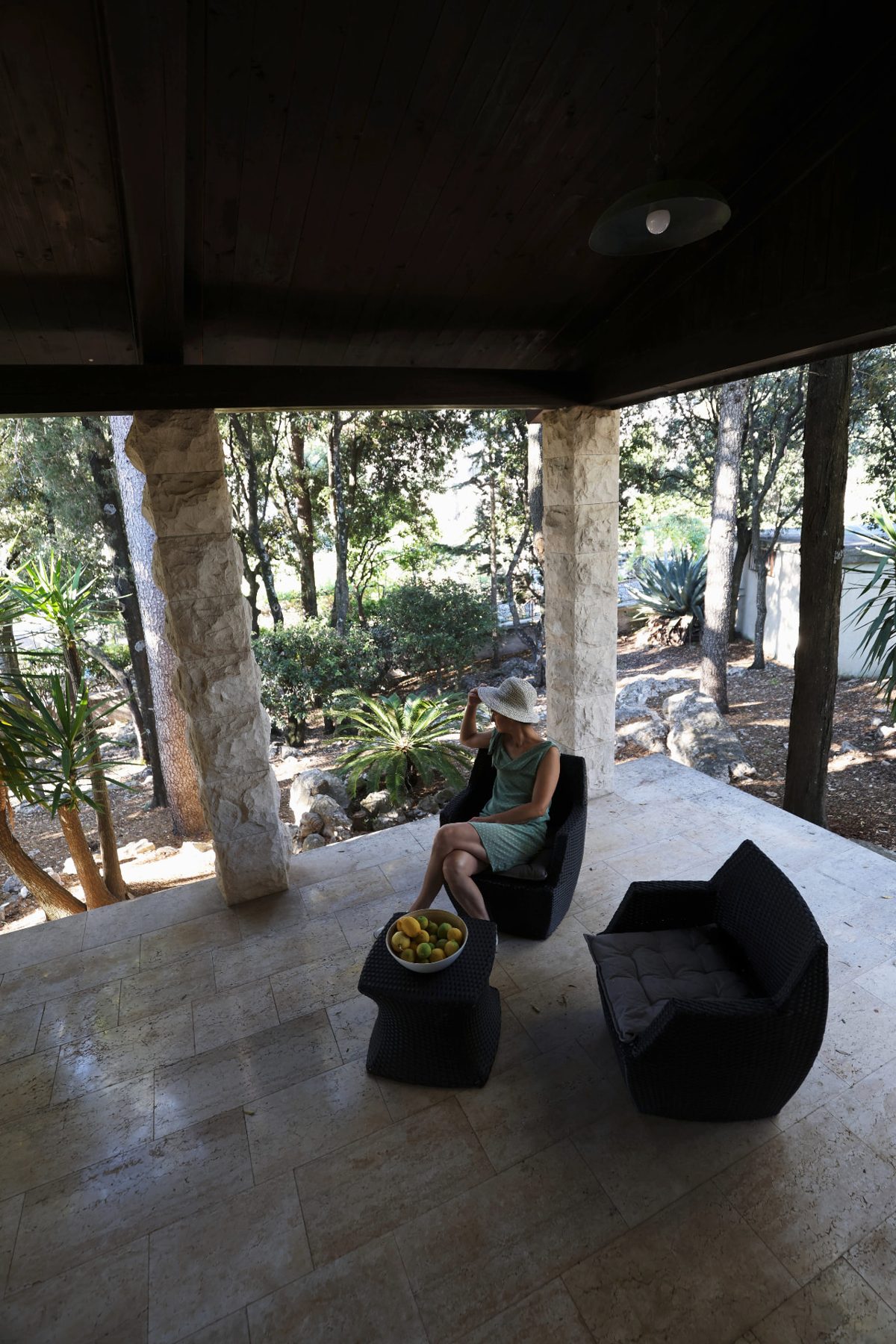 Someone resting in the shade of the terrace, trees and stone around