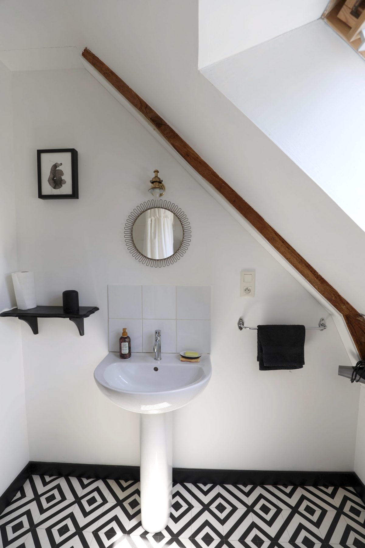 Bathroom basin under a sloping beam, with patterned black-and-white floor