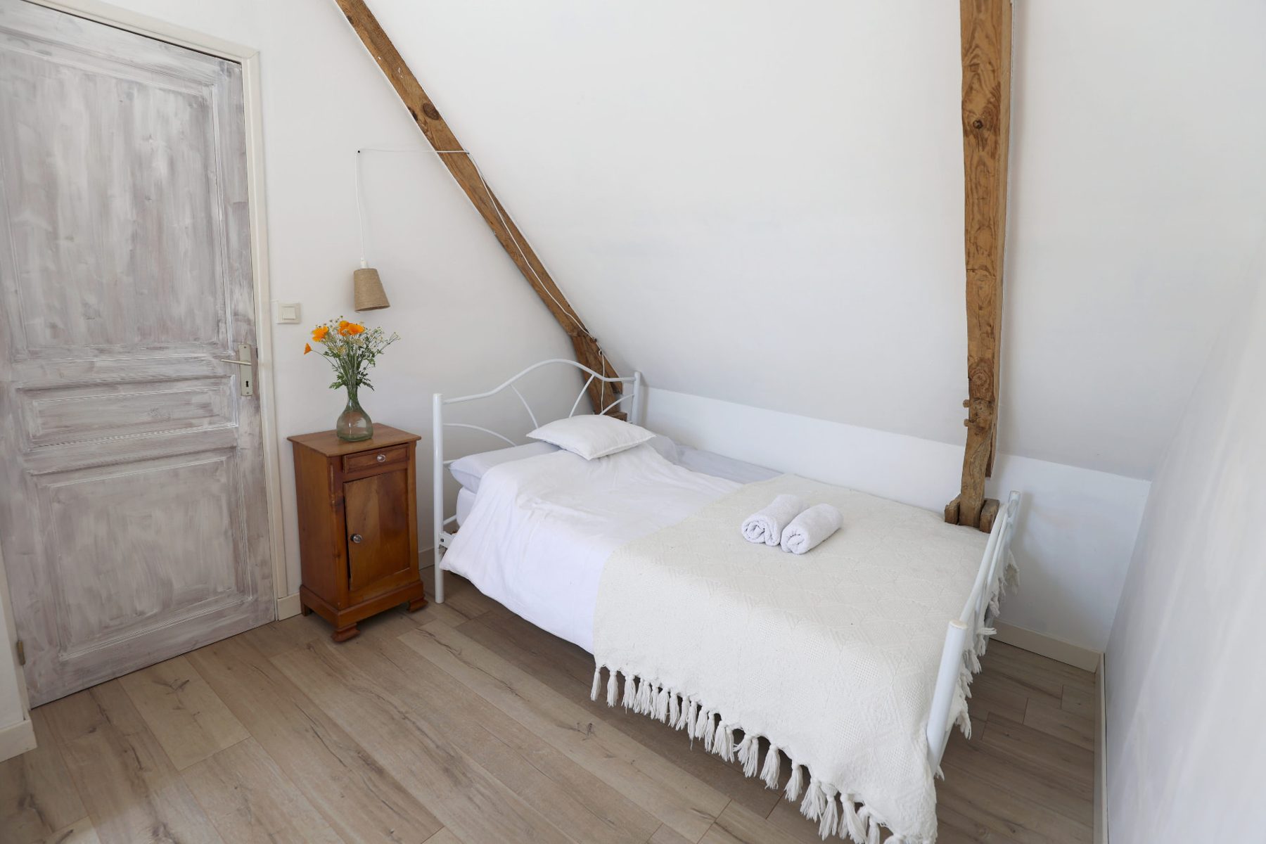 Bedroom with an iron bed under the exposed beams