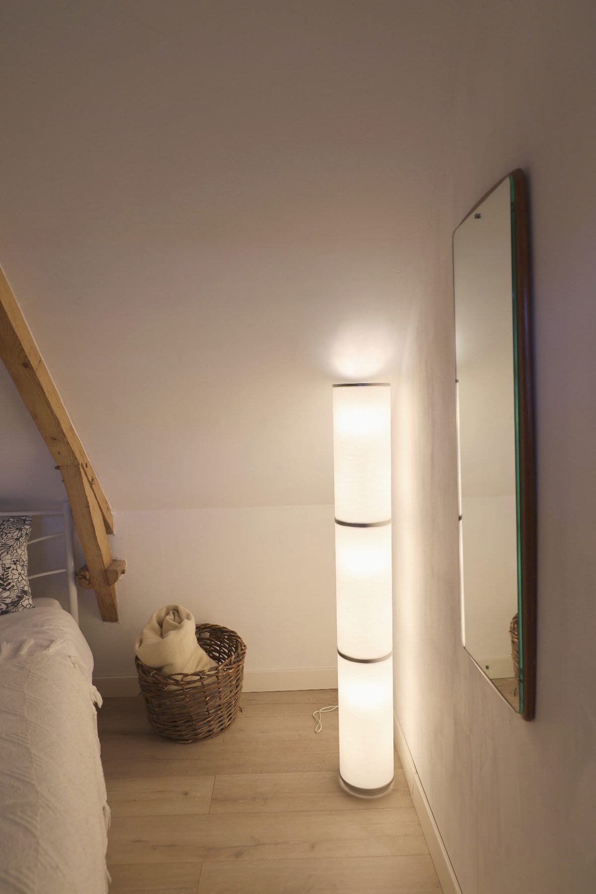 A paper floor lamp glowing in the corner of a bedroom