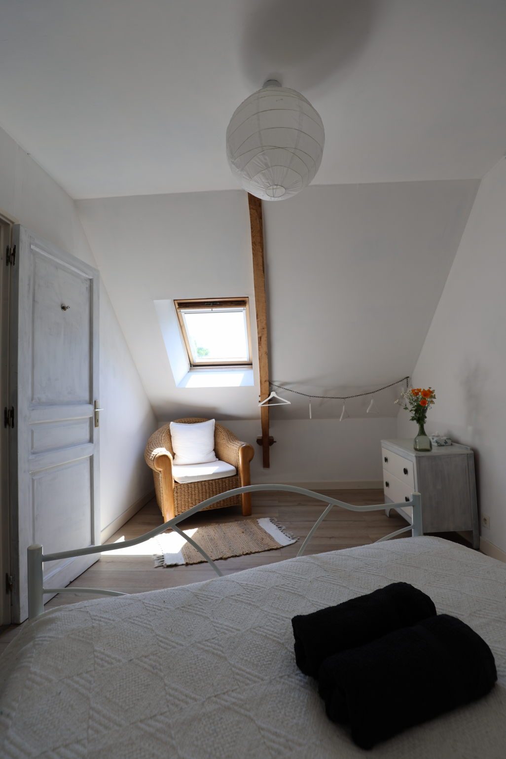Bedroom under the roof with a wicker armchair by the skylight