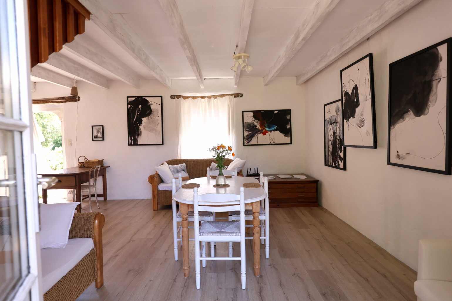 Living and dining room with white beams, a round table and large ink works on the walls