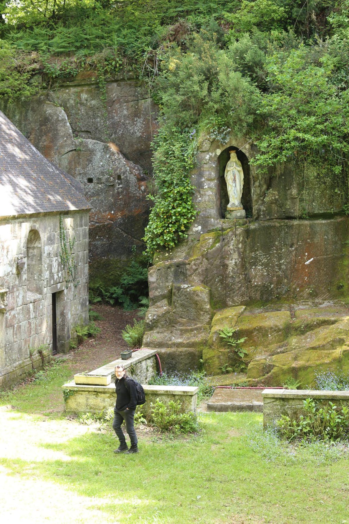 A small stone chapel and grotto amid greenery at Locuon